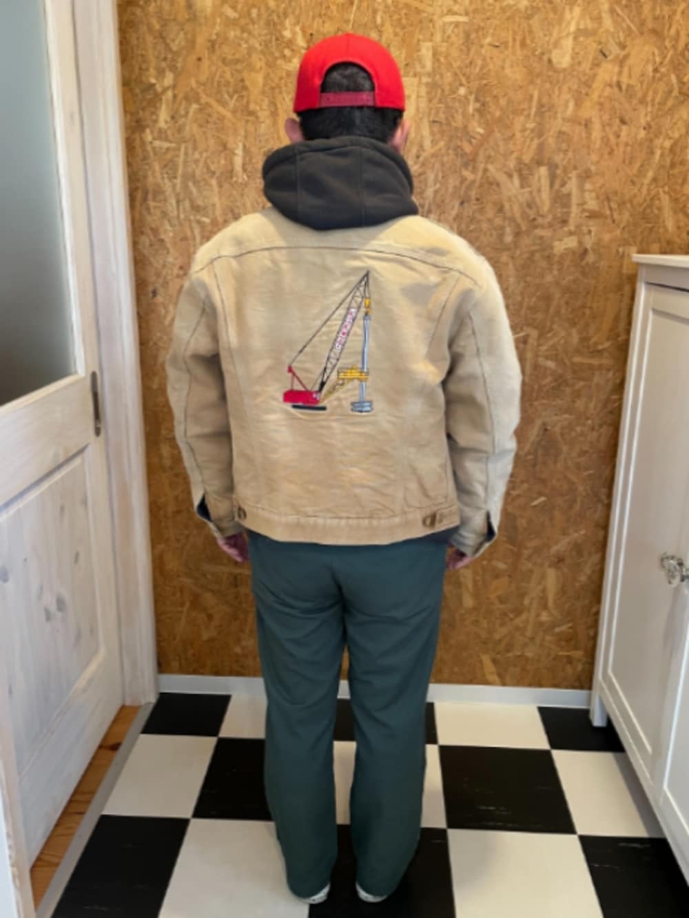 ベージュ系のジャケット/アウター、ブラック系のパーカー、グリーン系のチノパンツを着用したメンズの冬コーディネートの2枚目の写真