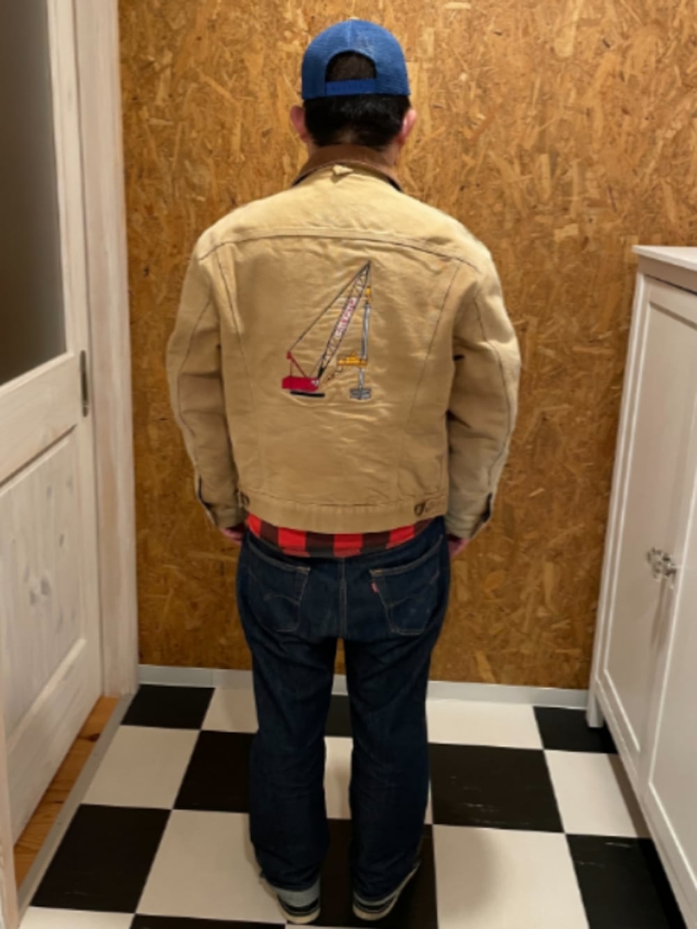 ベージュ系のジャケット/アウター、レッド系のシャツ/ブラウス、ブルー系のデニムパンツを着用したメンズの冬コーディネートの2枚目の写真