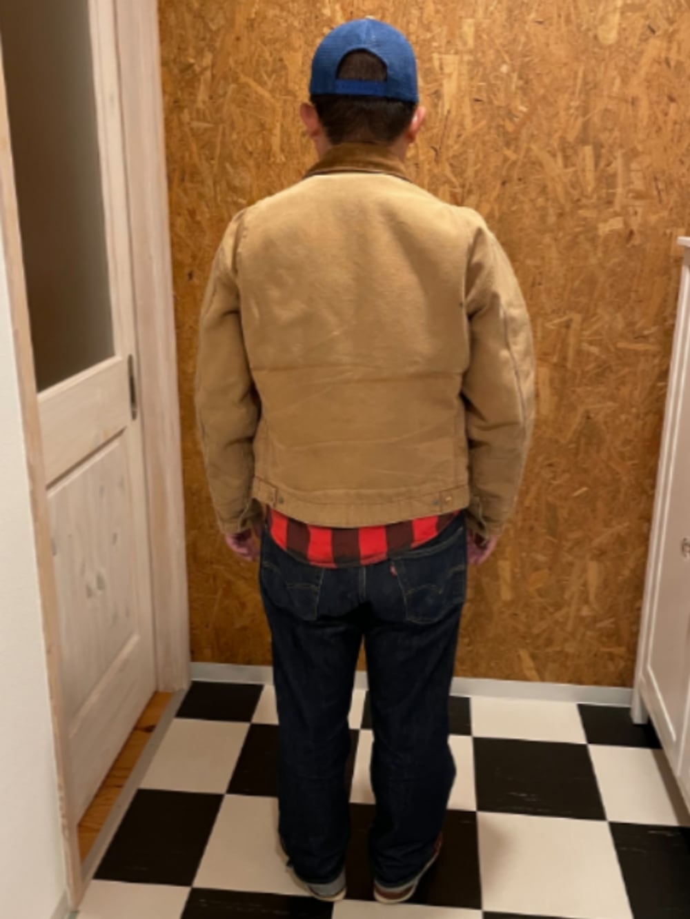 ベージュ系のジャケット/アウター、レッド系のシャツ/ブラウス、ブルー系のデニムパンツを着用したメンズの秋コーディネートの2枚目の写真