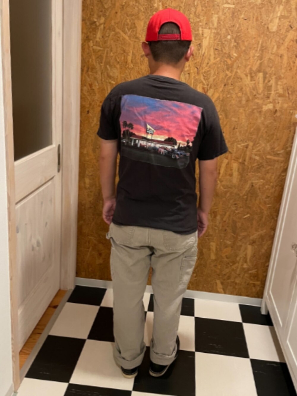 ブラック系のTシャツ/カットソー、ベージュ系のチノパンツ、ブラック系のブーツを着用したメンズの秋コーディネートの2枚目の写真