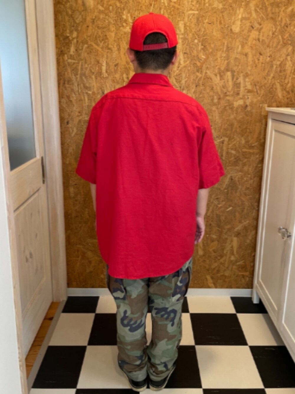 レッド系のシャツ/ブラウス、グリーン系のカーゴパンツ、ブラック系のブーツを着用したメンズの夏コーディネートの2枚目の写真