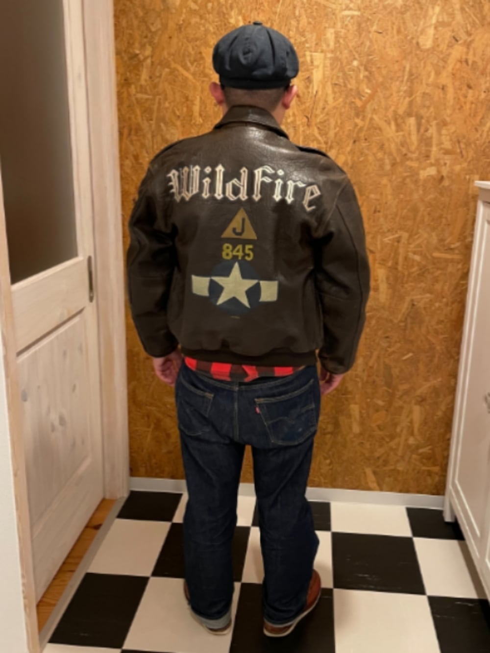 ブラウン系のその他アウター、レッド系のシャツ/ブラウス、ブルー系のデニムパンツを着用したメンズの冬コーディネートの2枚目の写真