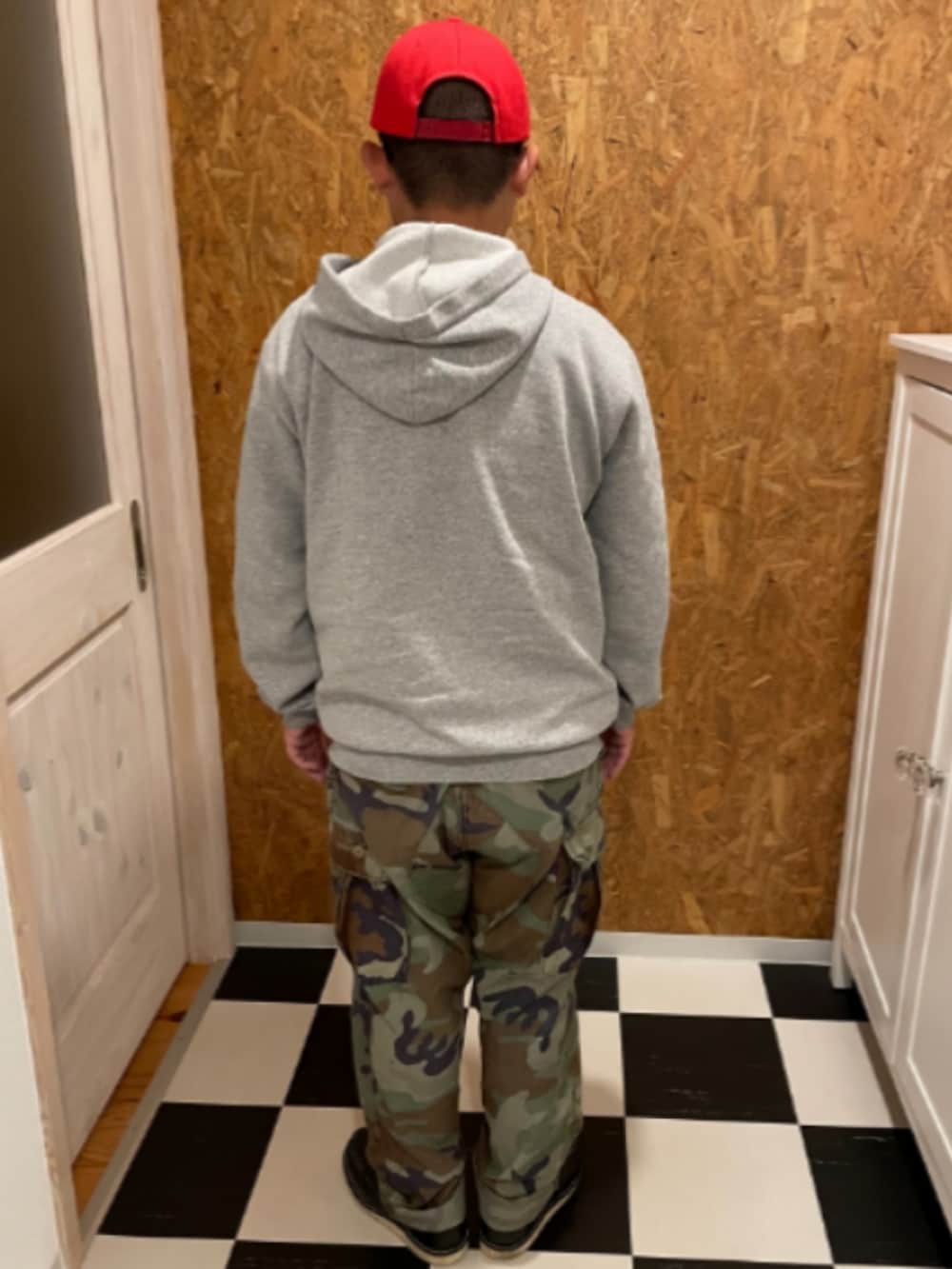 グレー系のパーカー、グリーン系のカーゴパンツ、ブラック系のブーツを着用したメンズの秋コーディネートの2枚目の写真