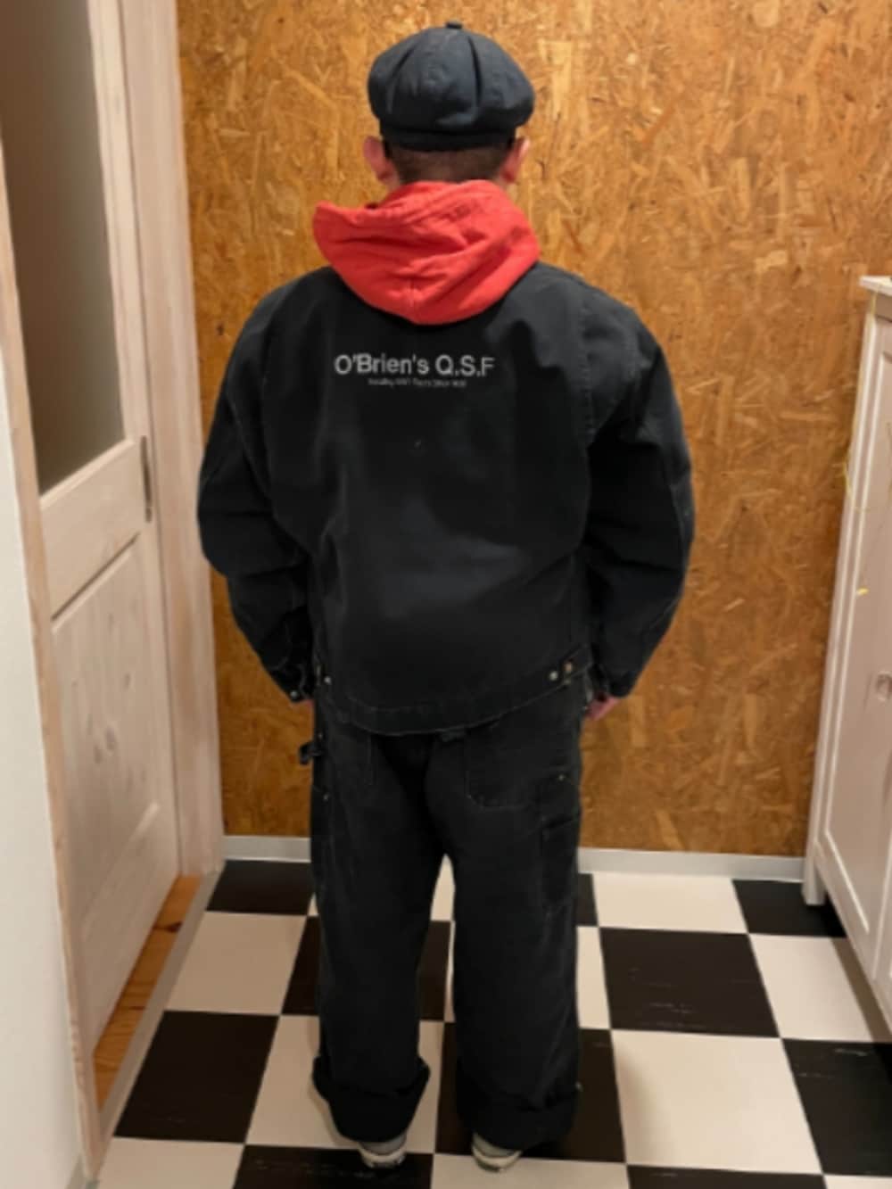 ブラック系のブルゾン、ブラック系のサロペット/オーバーオール、オレンジ系のパーカーを着用したメンズの冬コーディネートの2枚目の写真