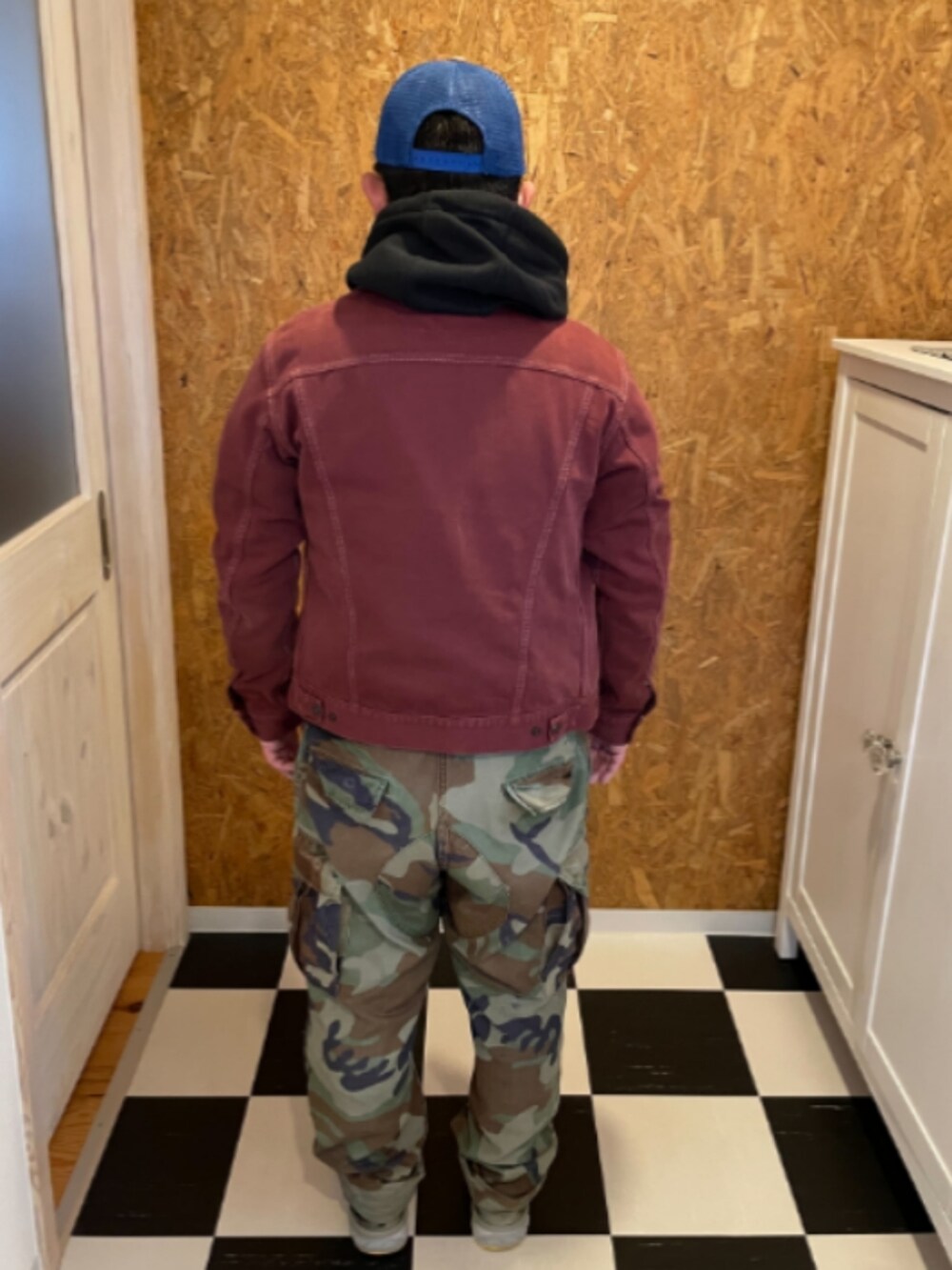 ブラック系のパーカー、レッド系のジャケット/アウター、グリーン系のカーゴパンツを着用したメンズの春コーディネートの2枚目の写真