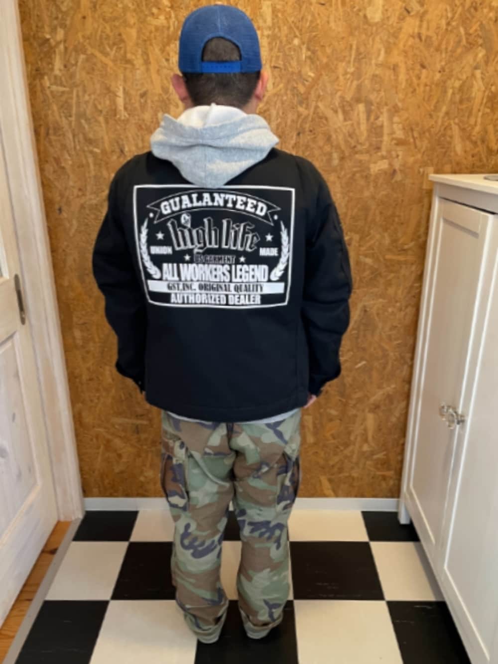 ブラック系のジャケット/アウター、グレー系のパーカー、グリーン系のカーゴパンツを着用したメンズの春コーディネートの2枚目の写真