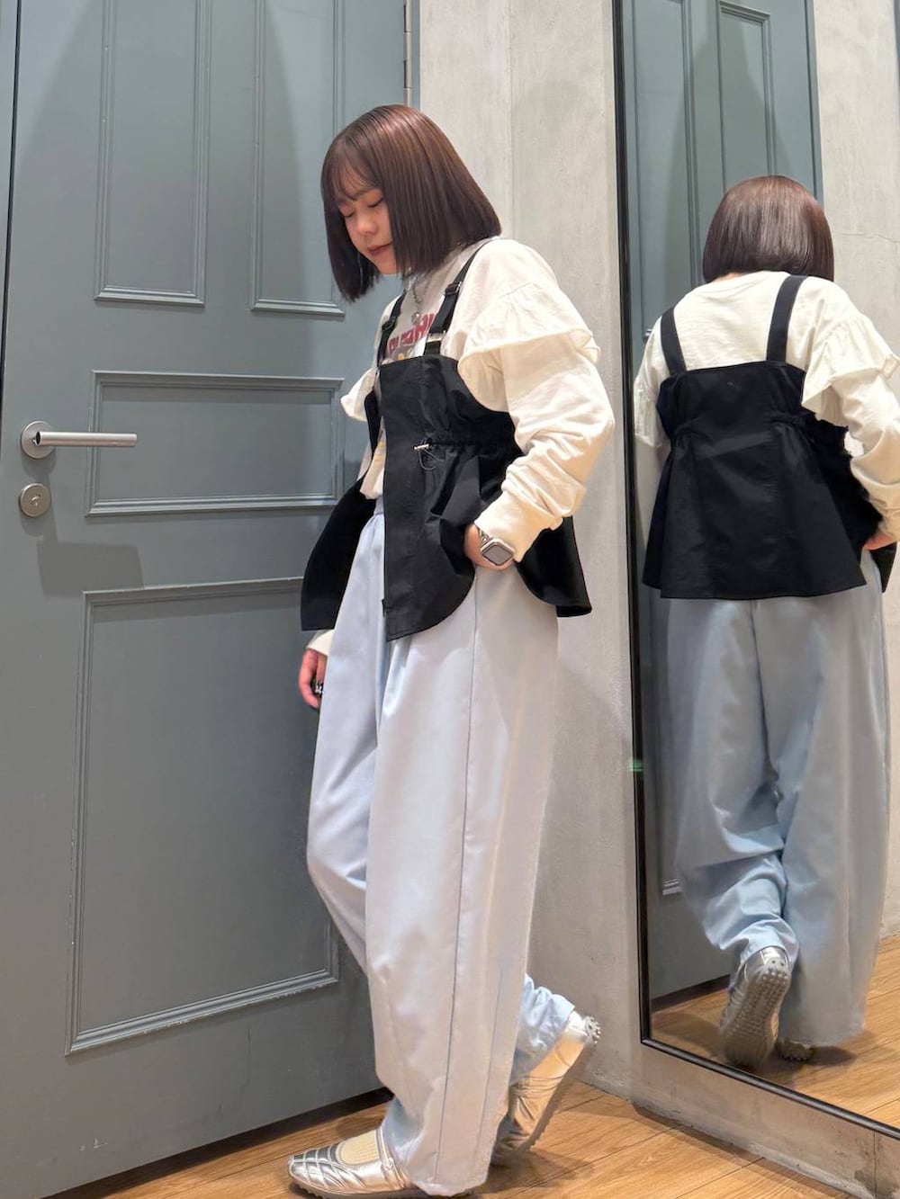 シルバー系のスニーカー、ブラック系のベスト、ホワイト系のTシャツ/カットソーを着用したレディースの春コーディネートの2枚目の写真