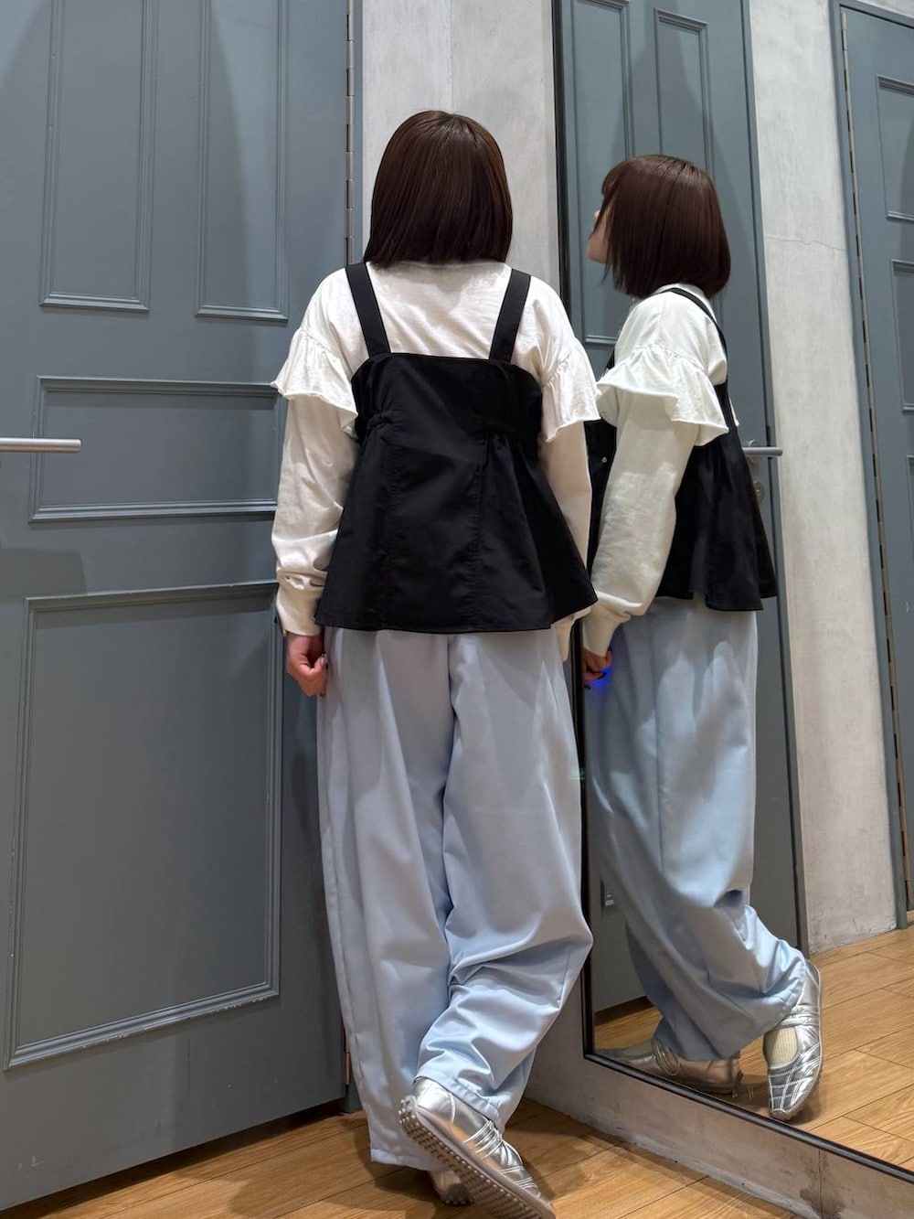 シルバー系のスニーカー、ブラック系のベスト、ホワイト系のTシャツ/カットソーを着用したレディースの春コーディネートの3枚目の写真