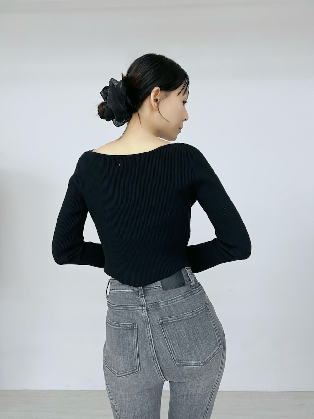 ブラック系のデニムパンツ、ブラック系のニット/セーター、ブラック系のブーツを着用したレディースの秋コーディネートの6枚目の写真