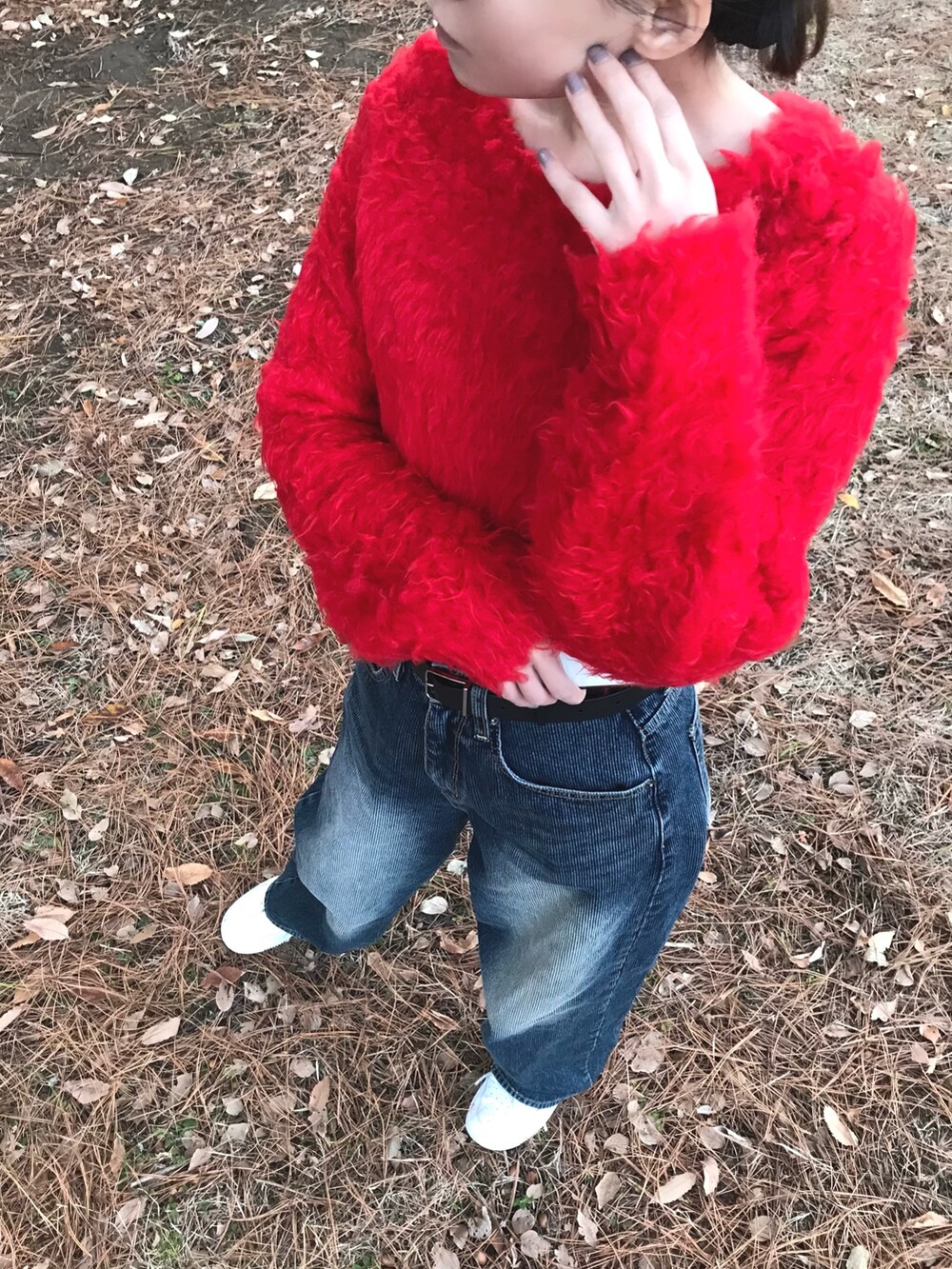 レッド系のニット/セーター、ブルー系のデニムパンツを着用したレディースの冬コーディネートの7枚目の写真