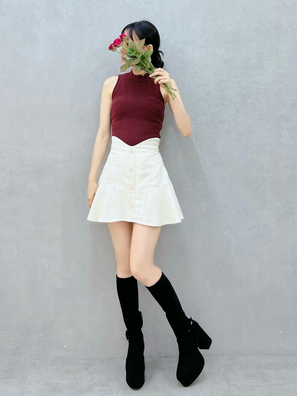 レッド系のニット/セーター、ホワイト系のスカート、ブラック系のブーツを着用したレディースの秋コーディネートの4枚目の写真