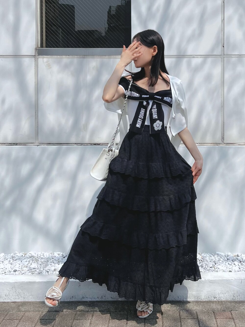 ブラック系のスカート、ホワイト系のワンピース、ホワイト系のサンダルを着用したレディースの春コーディネートの2枚目の写真