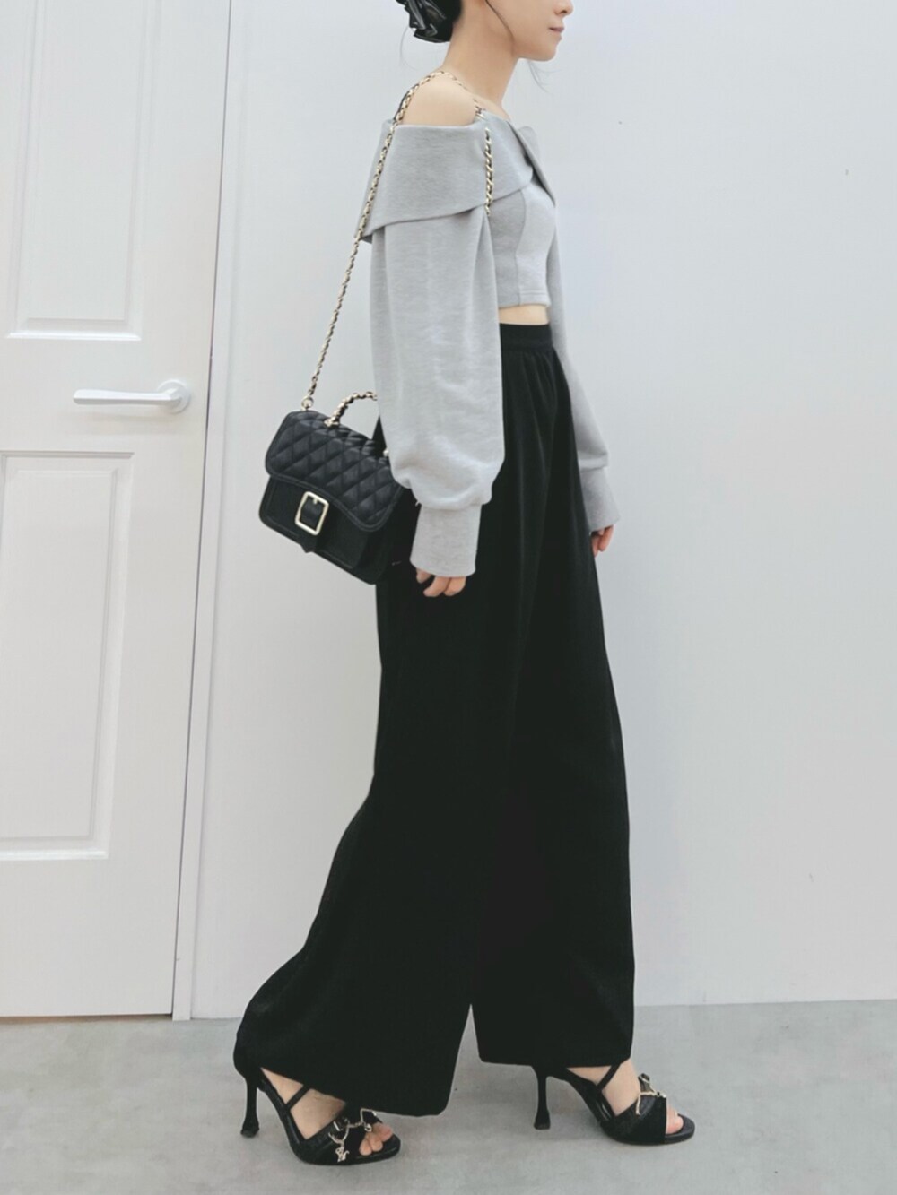 ブラック系のショルダーバッグ、ブラック系のサンダル、グレー系のTシャツ/カットソーを着用したレディースの夏コーディネートの3枚目の写真