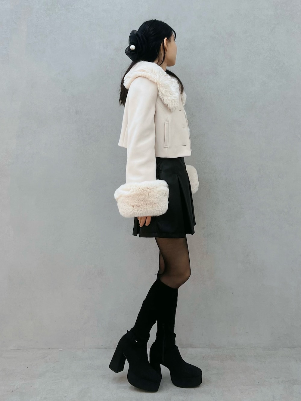 ブラック系のスカート、ホワイト系のその他アウター、ブラック系のブーツを着用したレディースの秋コーディネートの3枚目の写真