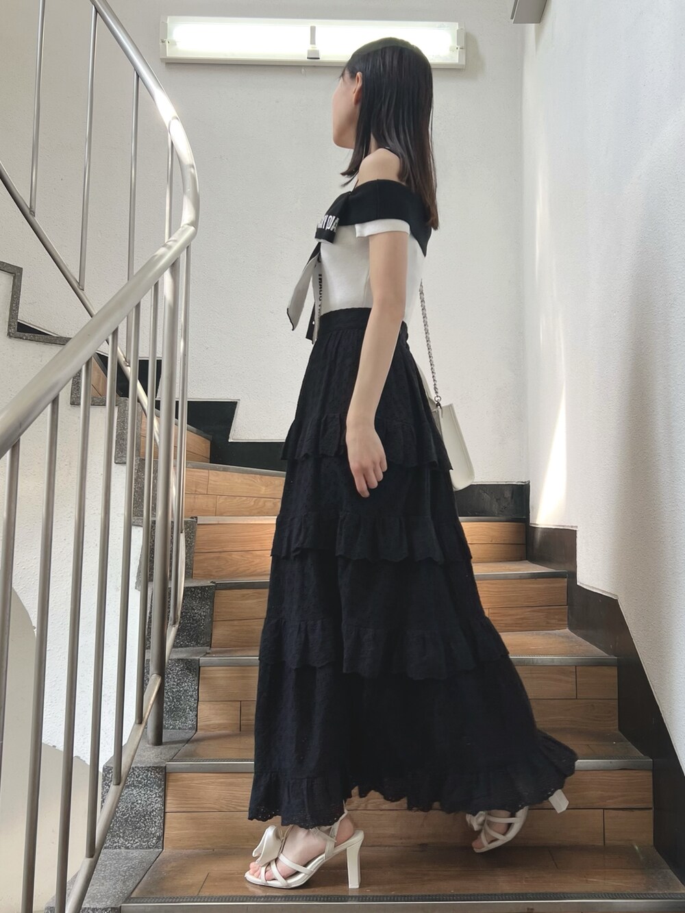 ブラック系のスカート、ホワイト系のワンピース、ホワイト系のサンダルを着用したレディースの春コーディネートの3枚目の写真