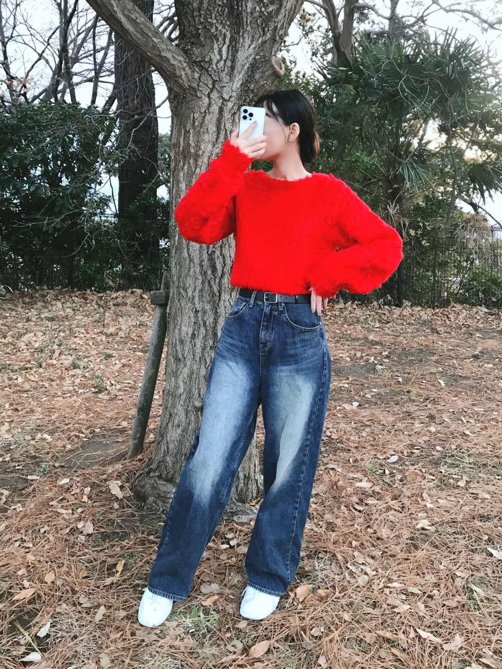 レッド系のニット/セーター、ブルー系のデニムパンツを着用したレディースの冬コーディネートの2枚目の写真