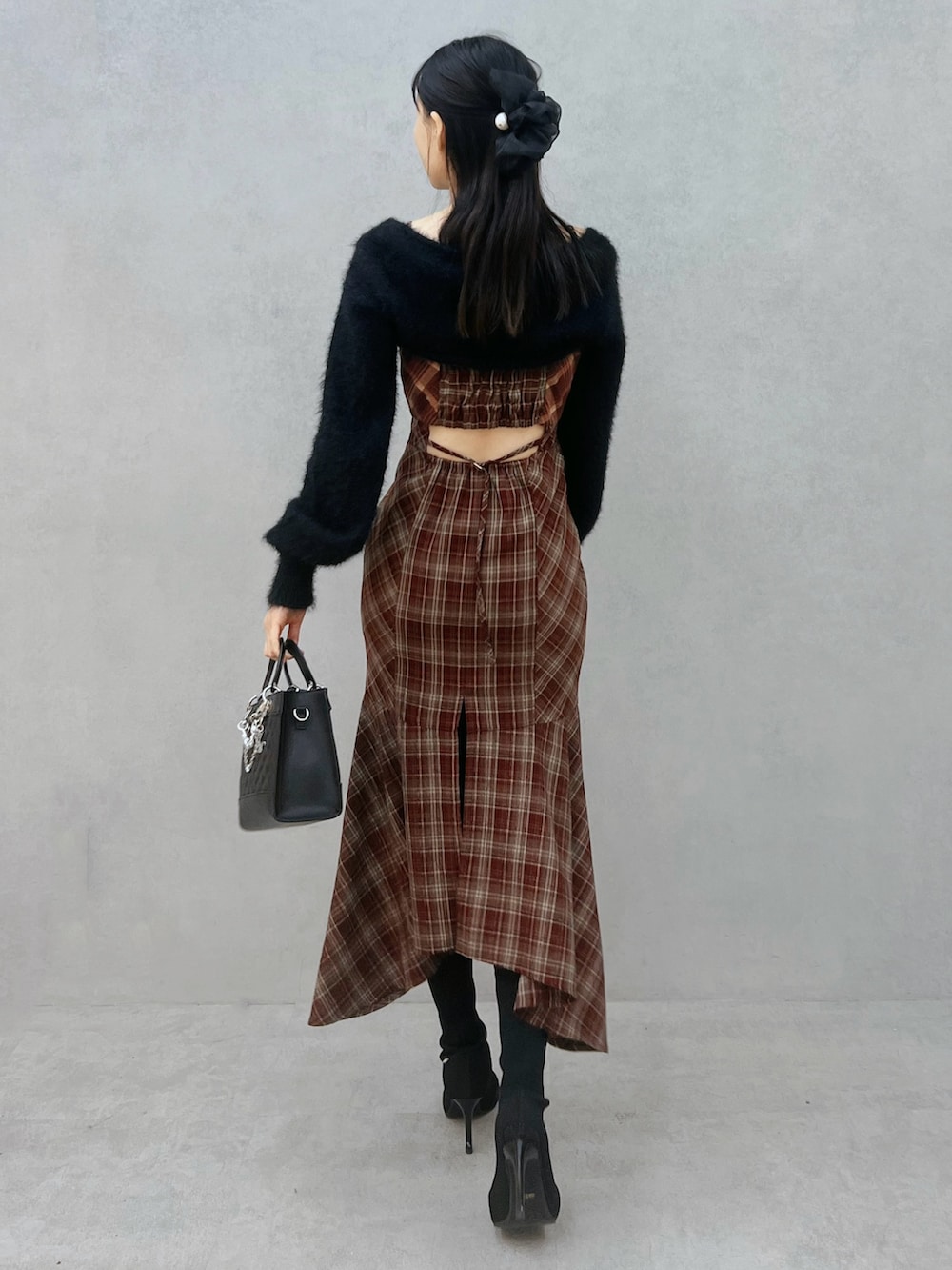 レッド系のワンピース、ブラック系のニット/セーター、ブラック系のブーツを着用したレディースの秋コーディネートの4枚目の写真