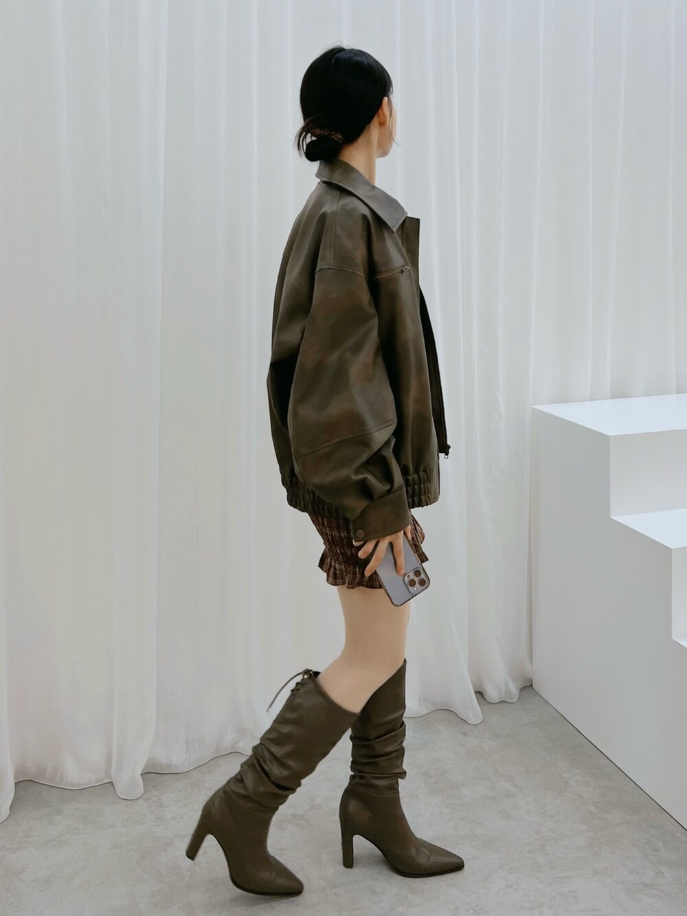 レッド系のワンピース、ブラウン系のブルゾン、ブラウン系のブーツを着用したレディースの秋コーディネートの2枚目の写真