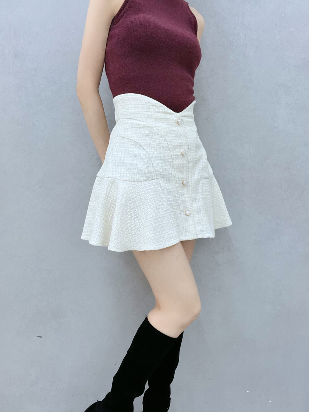 レッド系のニット/セーター、ホワイト系のスカート、ブラック系のブーツを着用したレディースの秋コーディネートの6枚目の写真