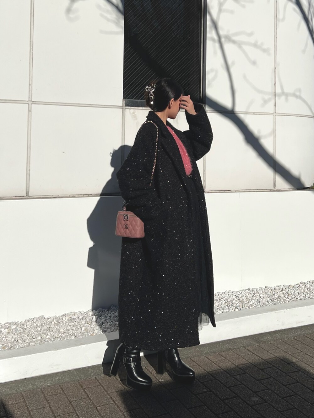 ピンク系のハンドバッグ、ブラック系のチェスターコート、ブラック系のブーツを着用したレディースの冬コーディネートの2枚目の写真