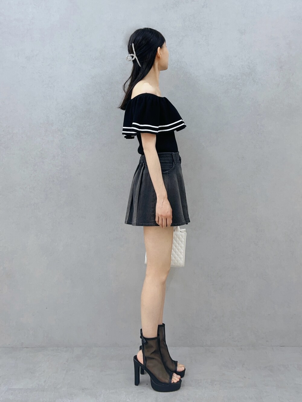 ブラック系のデニムスカート、ブラック系のサンダル、ホワイト系のハンドバッグを着用したレディースの夏コーディネートの4枚目の写真