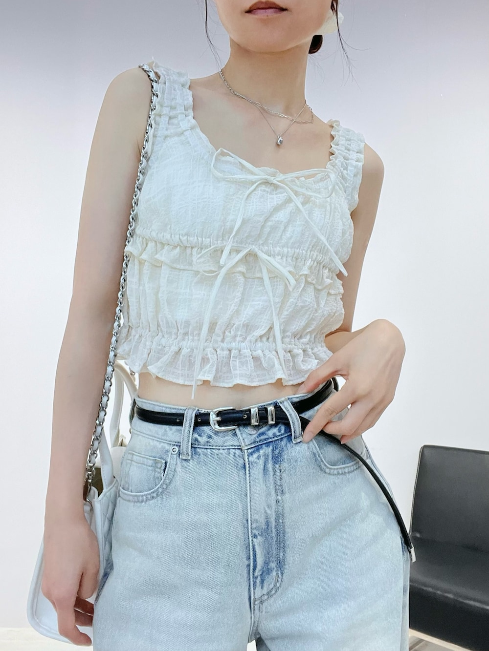 ブルー系のデニムパンツ、ホワイト系のサンダル、ホワイト系のキャミソールを着用したレディースの夏コーディネートの6枚目の写真