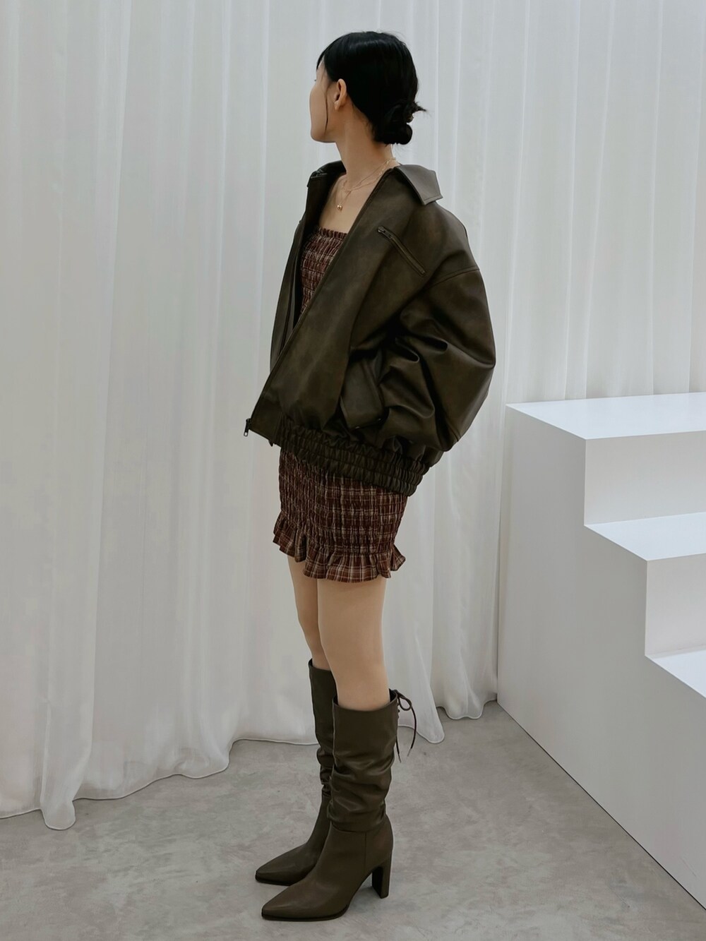 レッド系のワンピース、ブラウン系のブルゾン、ブラウン系のブーツを着用したレディースの秋コーディネートの5枚目の写真