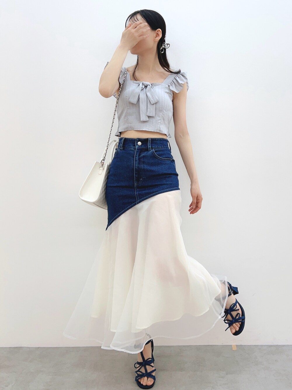 ブルー系のデニムスカート、ホワイト系のハンドバッグ、グレー系のシャツ/ブラウスを着用したレディースの春コーディネートの4枚目の写真