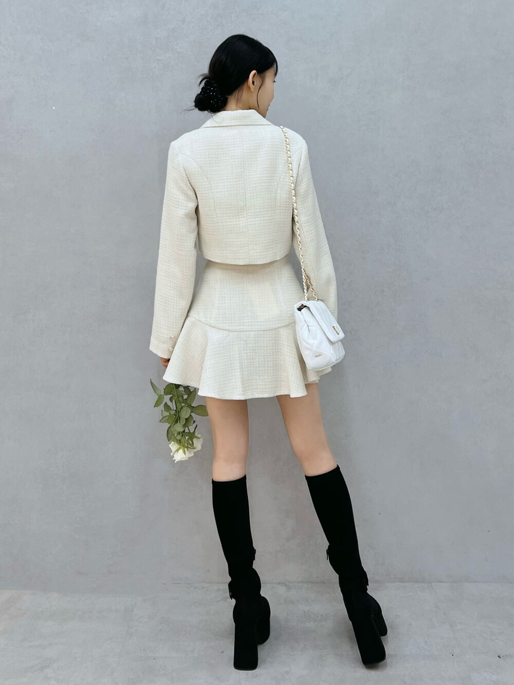 ホワイト系のテーラードジャケット、ブラック系のブーツ、ホワイト系のハンドバッグを着用したレディースの秋コーディネートの3枚目の写真