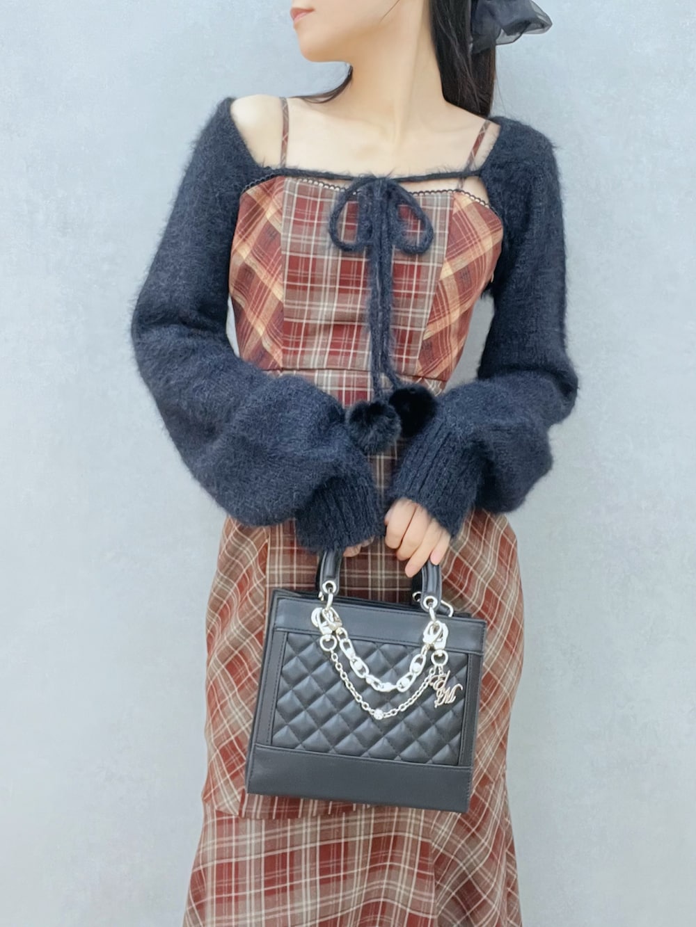 レッド系のワンピース、ブラック系のニット/セーター、ブラック系のブーツを着用したレディースの秋コーディネートの6枚目の写真