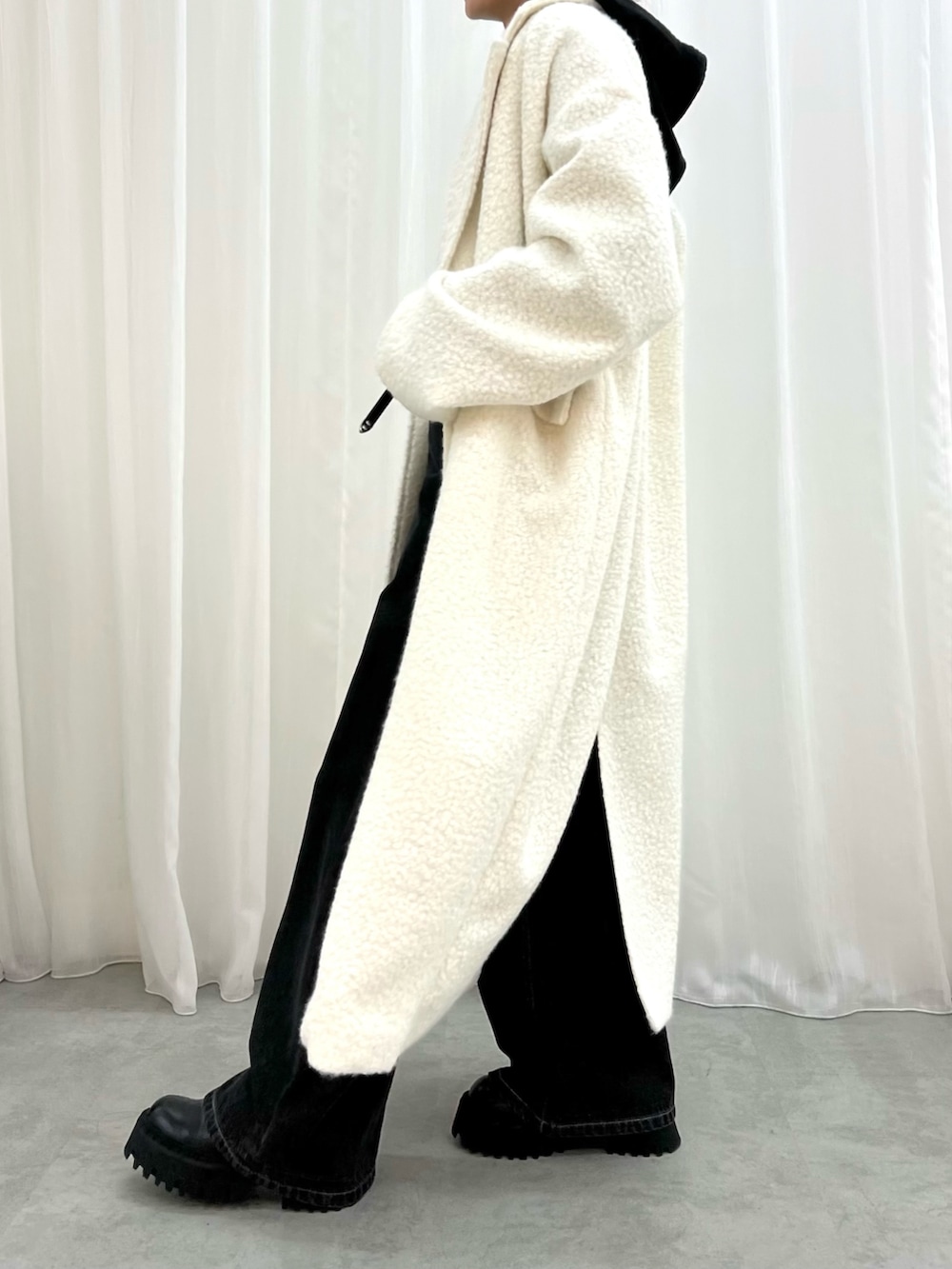 ブラック系のデニムパンツ、ホワイト系のチェスターコート、ブラック系のワンピースを着用したレディースの冬コーディネートの4枚目の写真