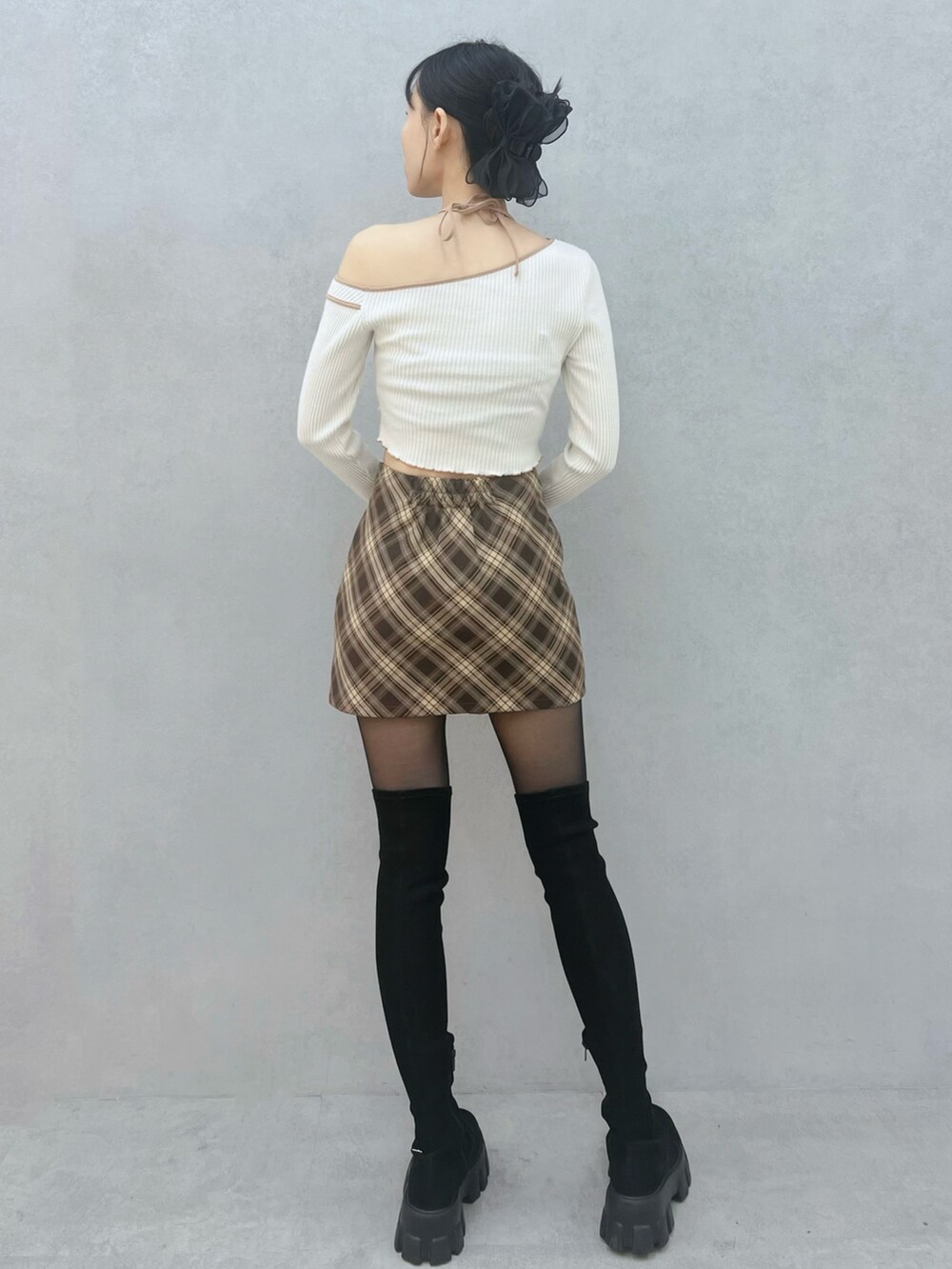 ブラウン系のスカート、ホワイト系のTシャツ/カットソー、ブラック系のブーツを着用したレディースの秋コーディネートの3枚目の写真