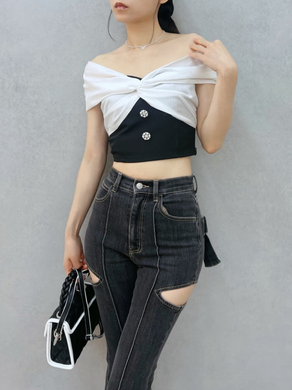 ブラック系のハンドバッグ、ブラック系のパンプス、ブラック系のデニムパンツを着用したレディースの夏コーディネートの5枚目の写真
