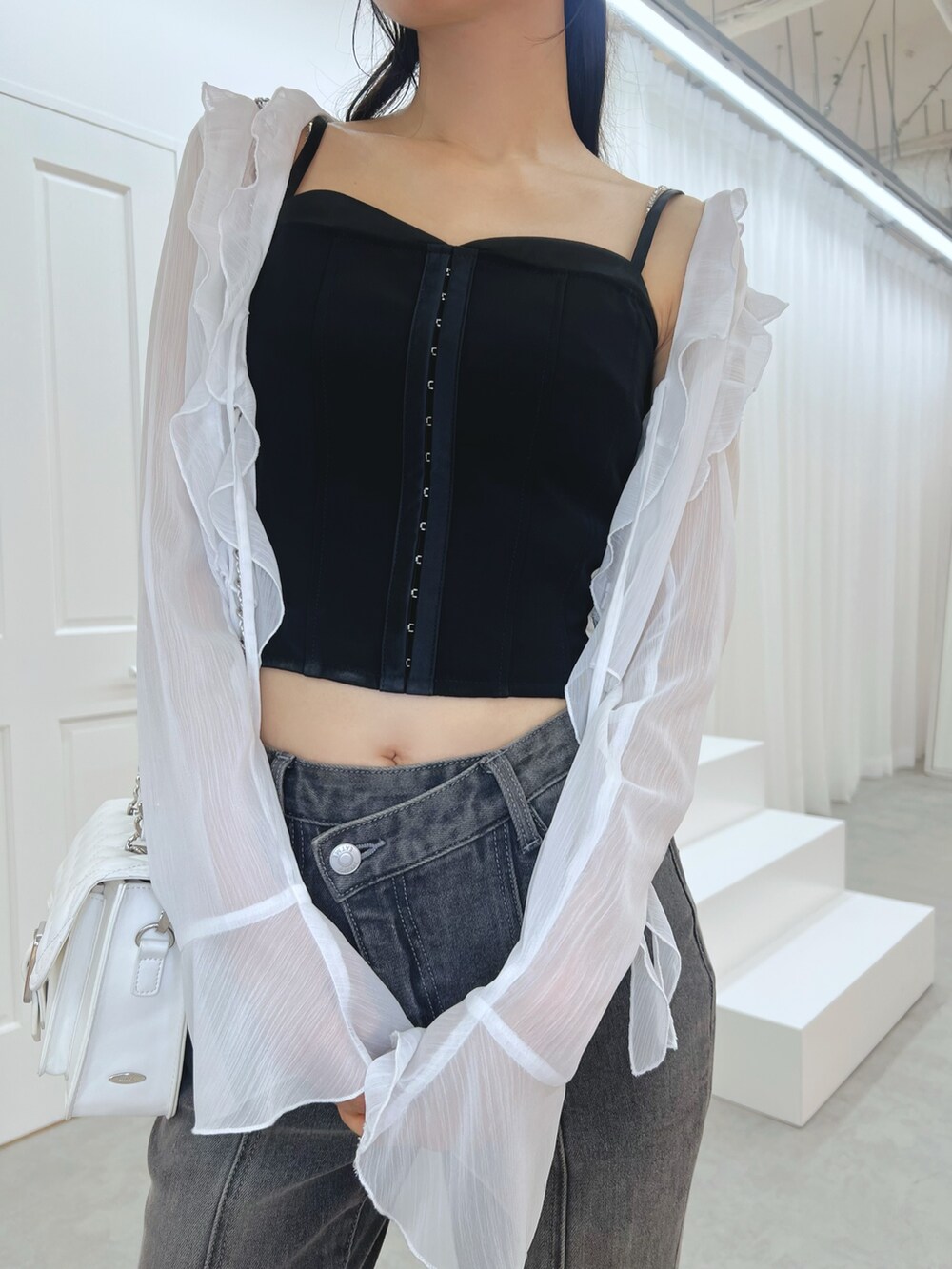 ブラック系のデニムパンツ、ブラック系のキャミソール、ホワイト系のカーディガン/ボレロを着用したレディースの秋コーディネートの4枚目の写真