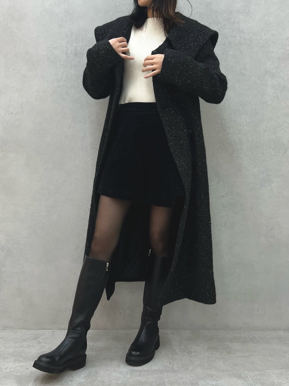 ブラック系のチェスターコート、レッド系のショルダーバッグ、ホワイト系のニット/セーターを着用したレディースの冬コーディネートの6枚目の写真