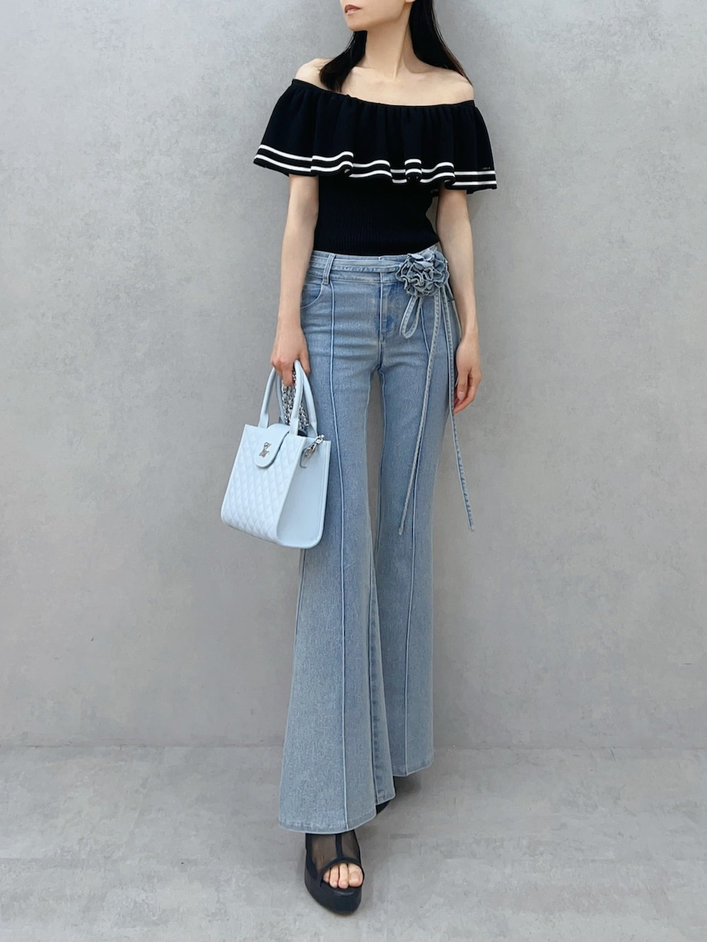 ブルー系のハンドバッグ、ブルー系のデニムパンツ、ブラック系のニット/セーターを着用したレディースの夏コーディネートの2枚目の写真