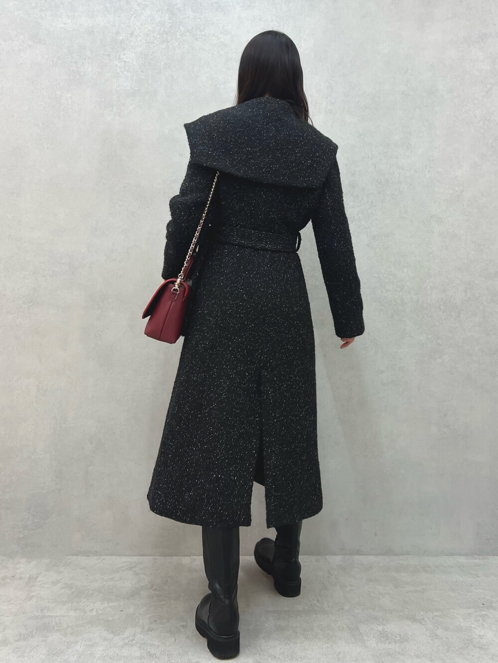 ブラック系のチェスターコート、レッド系のショルダーバッグ、ホワイト系のニット/セーターを着用したレディースの冬コーディネートの4枚目の写真