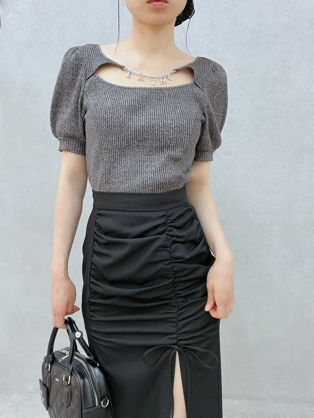 グレー系のTシャツ/カットソー、ブラック系のスカート、ブラック系のハンドバッグを着用したレディースの春コーディネートの6枚目の写真