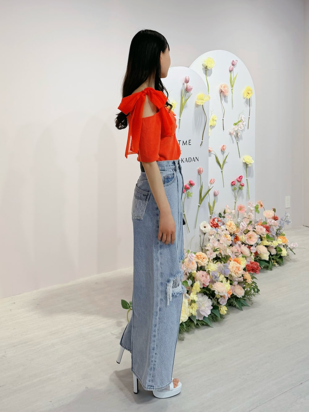 ブルー系のデニムパンツ、オレンジ系のTシャツ/カットソー、ホワイト系のブーツを着用したレディースの春コーディネートの2枚目の写真