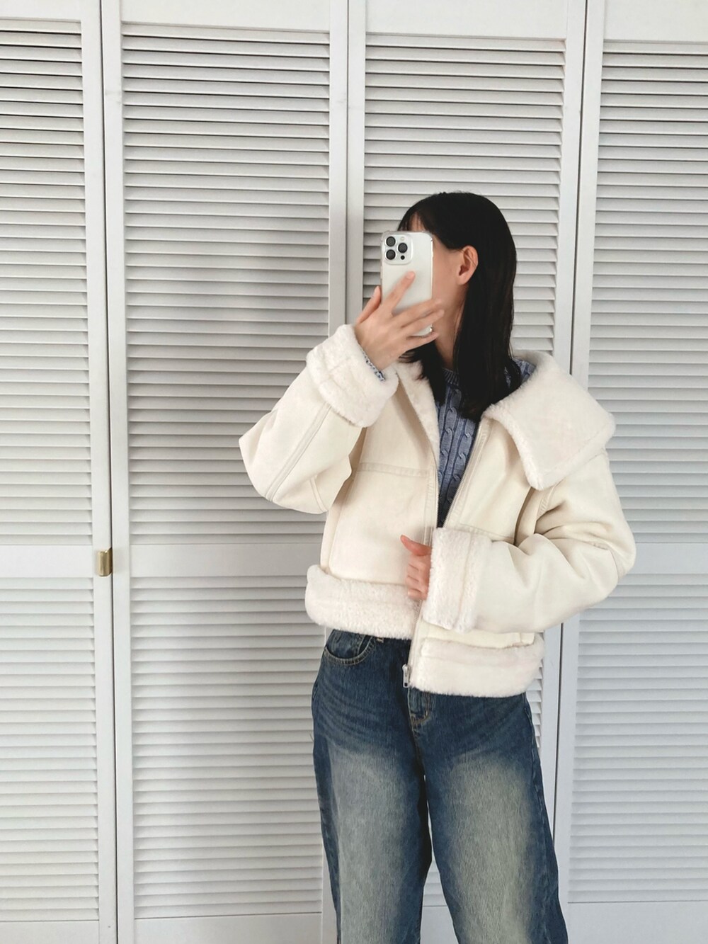 ホワイト系のブルゾン、ブルー系のデニムパンツを着用したレディースの冬コーディネートの2枚目の写真