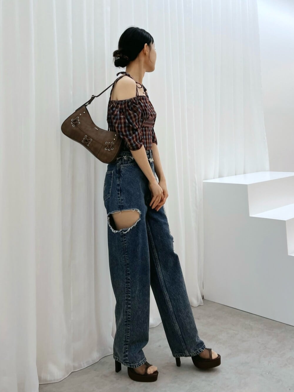ブラウン系のショルダーバッグ、ブルー系のデニムパンツ、ブラウン系のサンダルを着用したレディースの秋コーディネートの2枚目の写真