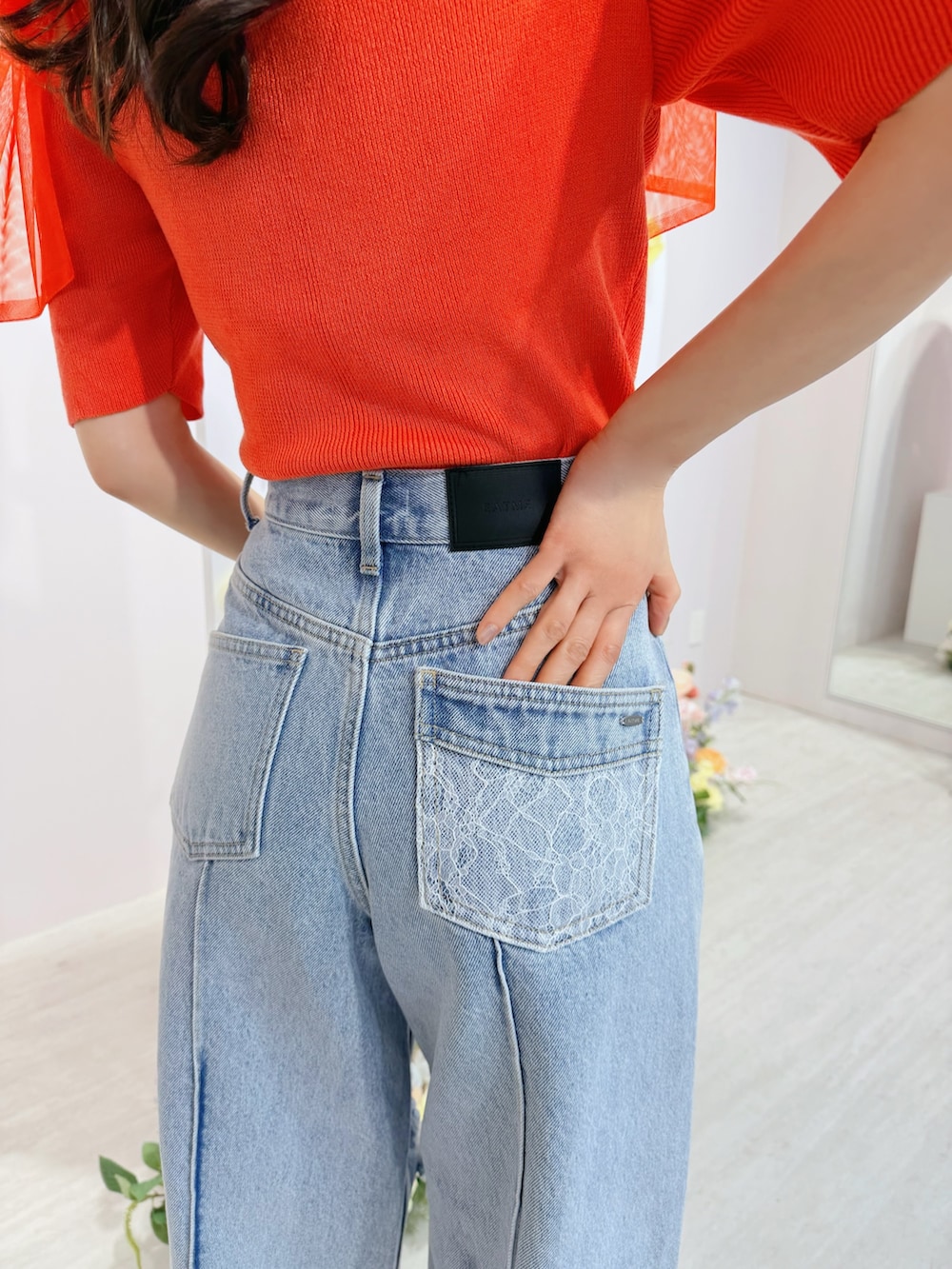 ブルー系のデニムパンツ、オレンジ系のTシャツ/カットソー、ホワイト系のブーツを着用したレディースの春コーディネートの4枚目の写真