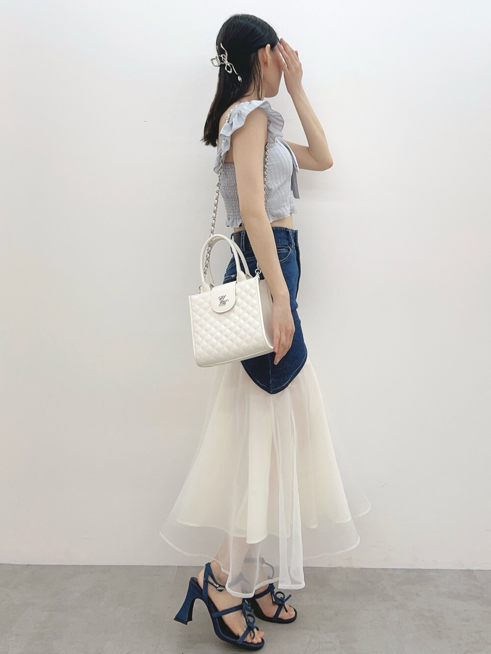 ブルー系のデニムスカート、ホワイト系のハンドバッグ、グレー系のシャツ/ブラウスを着用したレディースの春コーディネートの5枚目の写真