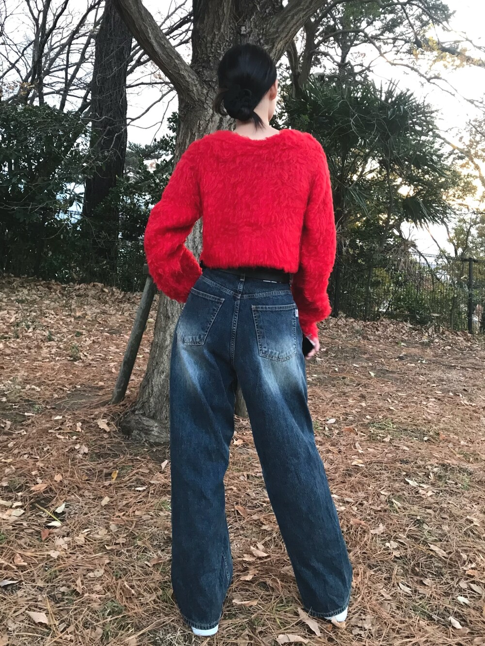 レッド系のニット/セーター、ブルー系のデニムパンツを着用したレディースの冬コーディネートの5枚目の写真