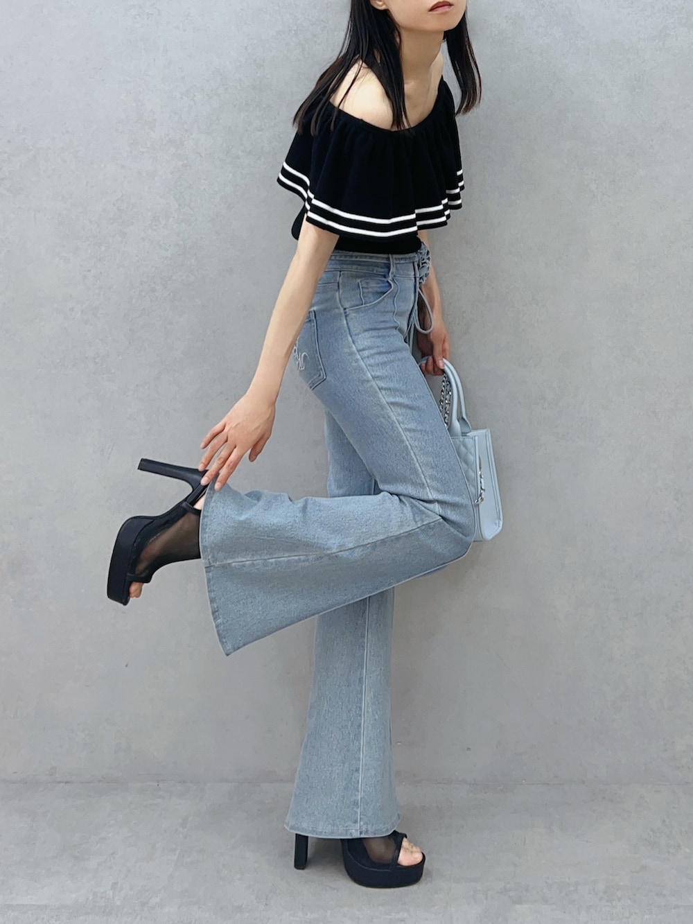 ブルー系のハンドバッグ、ブルー系のデニムパンツ、ブラック系のニット/セーターを着用したレディースの夏コーディネートの6枚目の写真