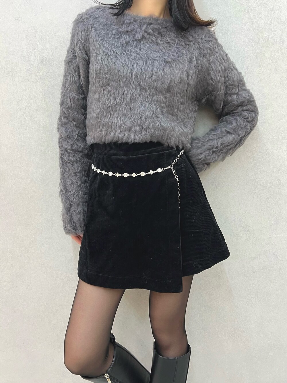 グレー系のニット/セーター、シルバー系のベルトを着用したレディースの冬コーディネートの2枚目の写真