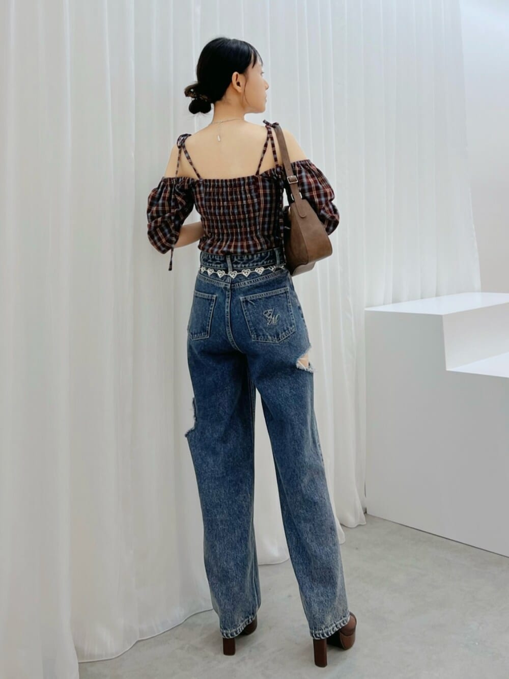 ブラウン系のショルダーバッグ、ブルー系のデニムパンツ、ブラウン系のサンダルを着用したレディースの秋コーディネートの3枚目の写真