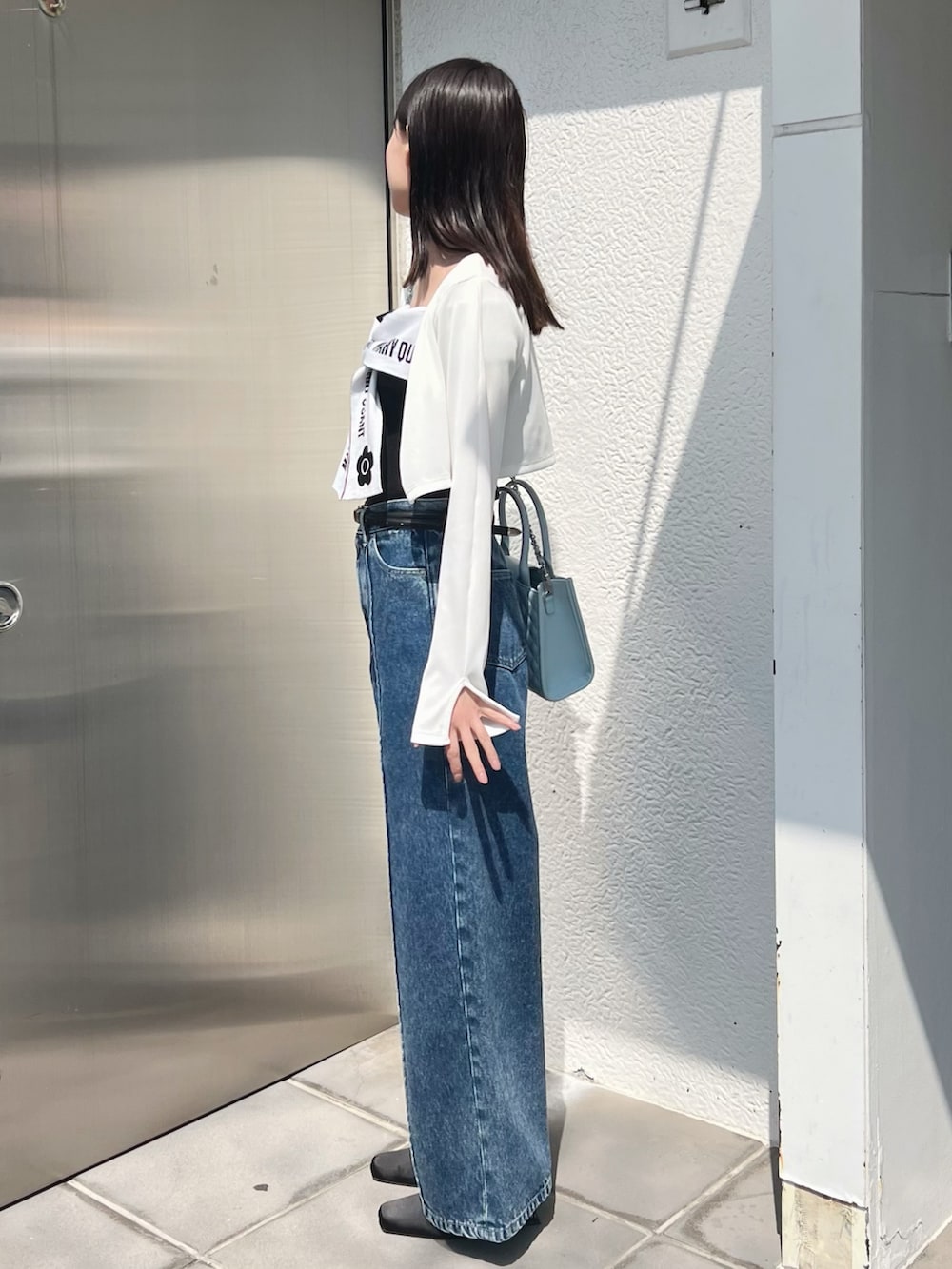 ブラック系のワンピース、ホワイト系のTシャツ/カットソー、ブルー系のハンドバッグを着用したレディースの春コーディネートの5枚目の写真