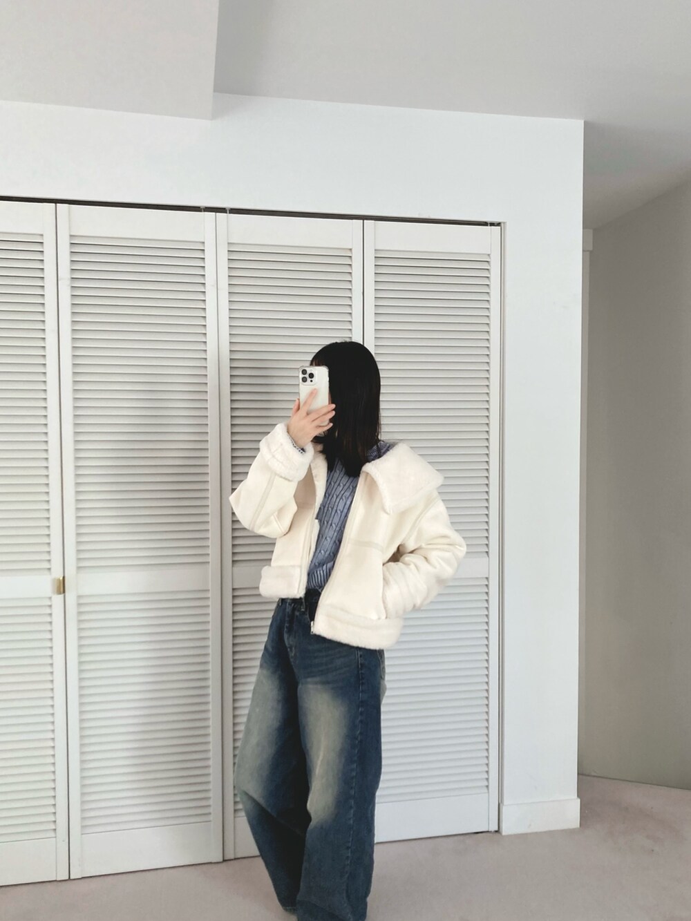 ホワイト系のブルゾン、ブルー系のデニムパンツを着用したレディースの冬コーディネートの5枚目の写真