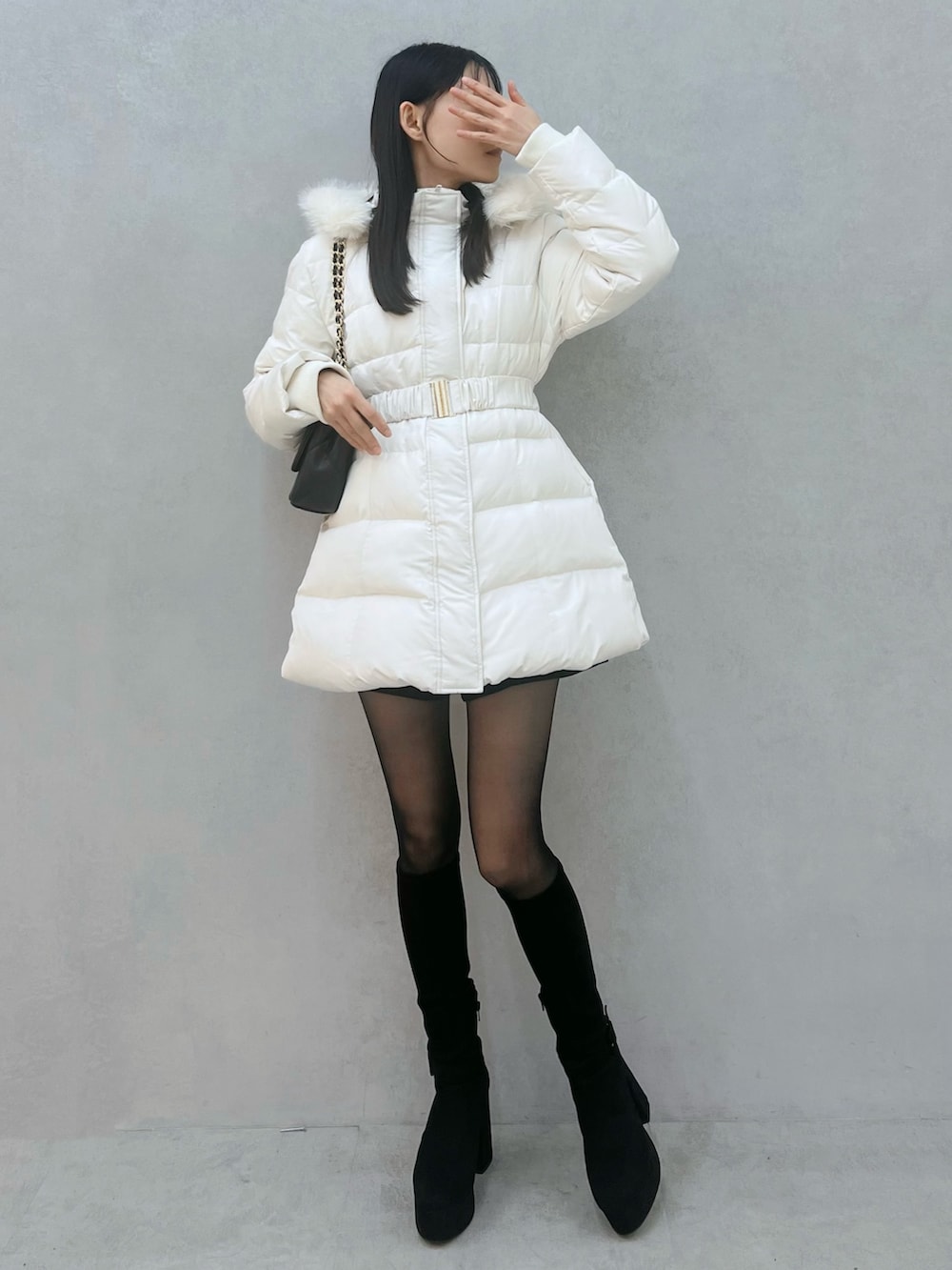 ブラック系のダウンジャケット/コート、ブラック系のブーツ、ブラック系のハンドバッグを着用したレディースの秋コーディネートの2枚目の写真